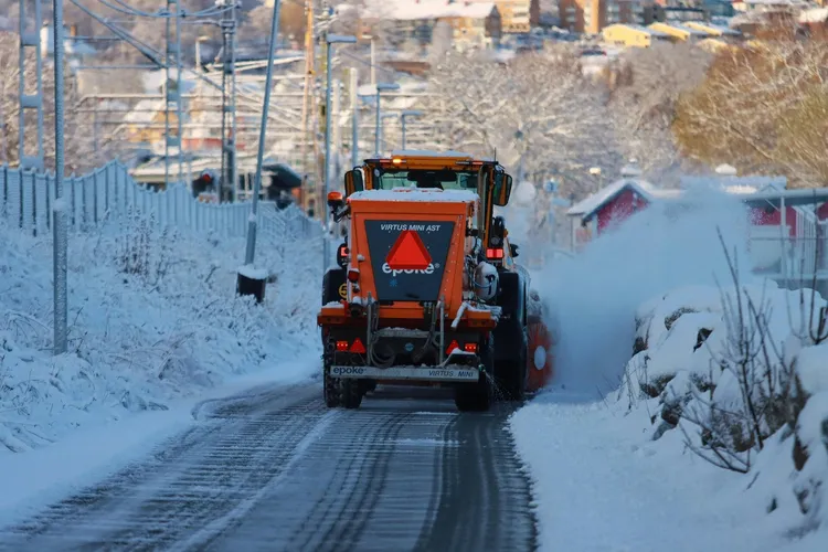 Traktor som röjer en snötäckt väg, illustration av vinterunderhåll.